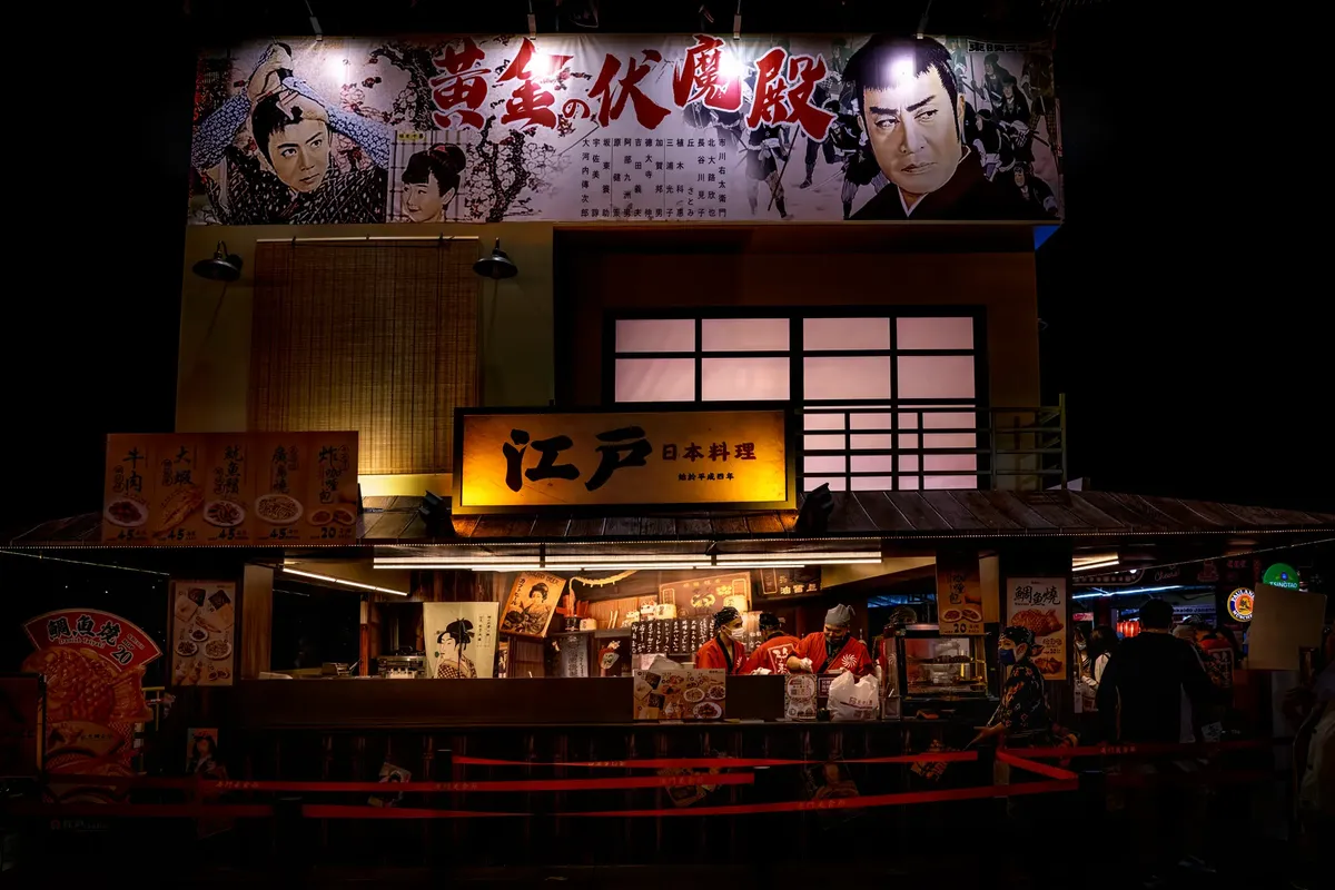 A bustling Japanese street food stall illuminated at night, showcasing traditional decor.