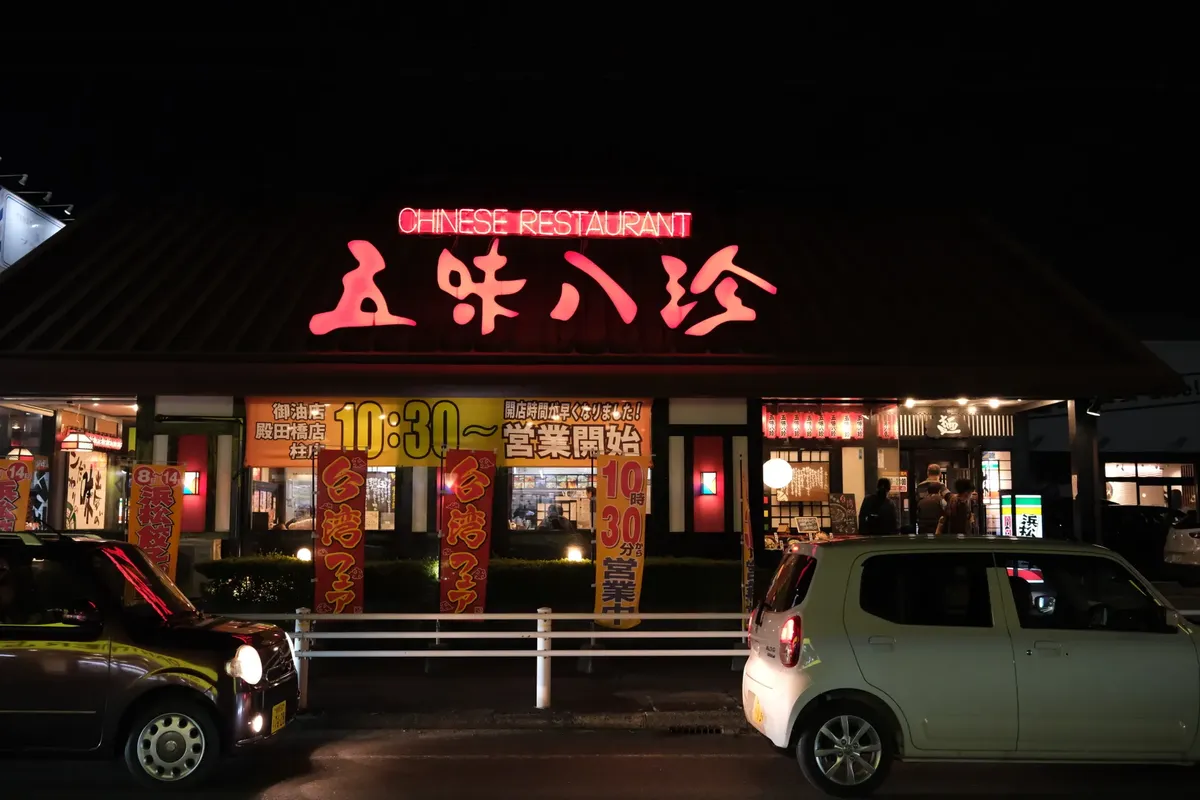 Illuminated Chinese restaurant in Toyohashi, Japan with cars at night.
